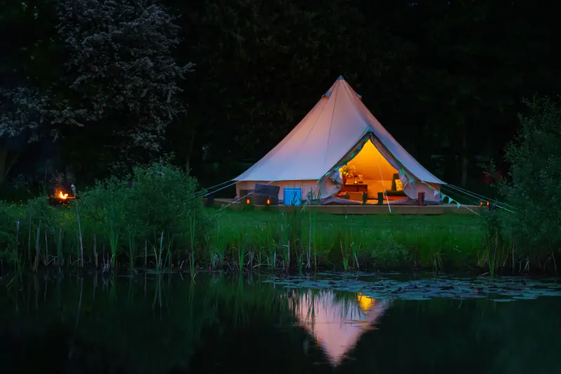 Bell tent at dusk with campfire glowing at Chalke Valley Camping