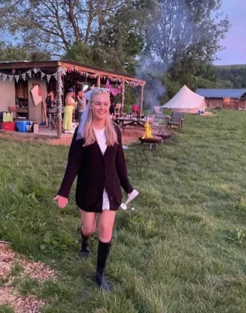 Hen party guest with cowboy hat walking towards the shelter and bell tents at Chalke Valley