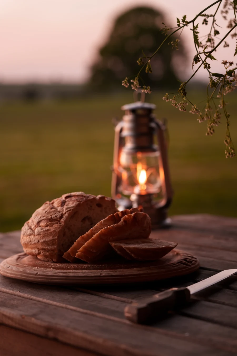 Fresh bread and lantern at dusk at Chalke Valley Camping
