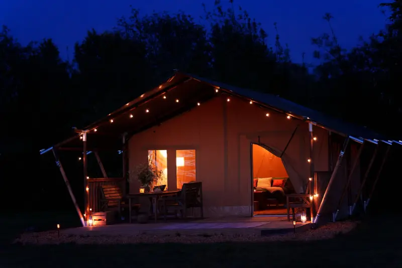 Safari tent exterior with fairy lights and a peek inside through the open door